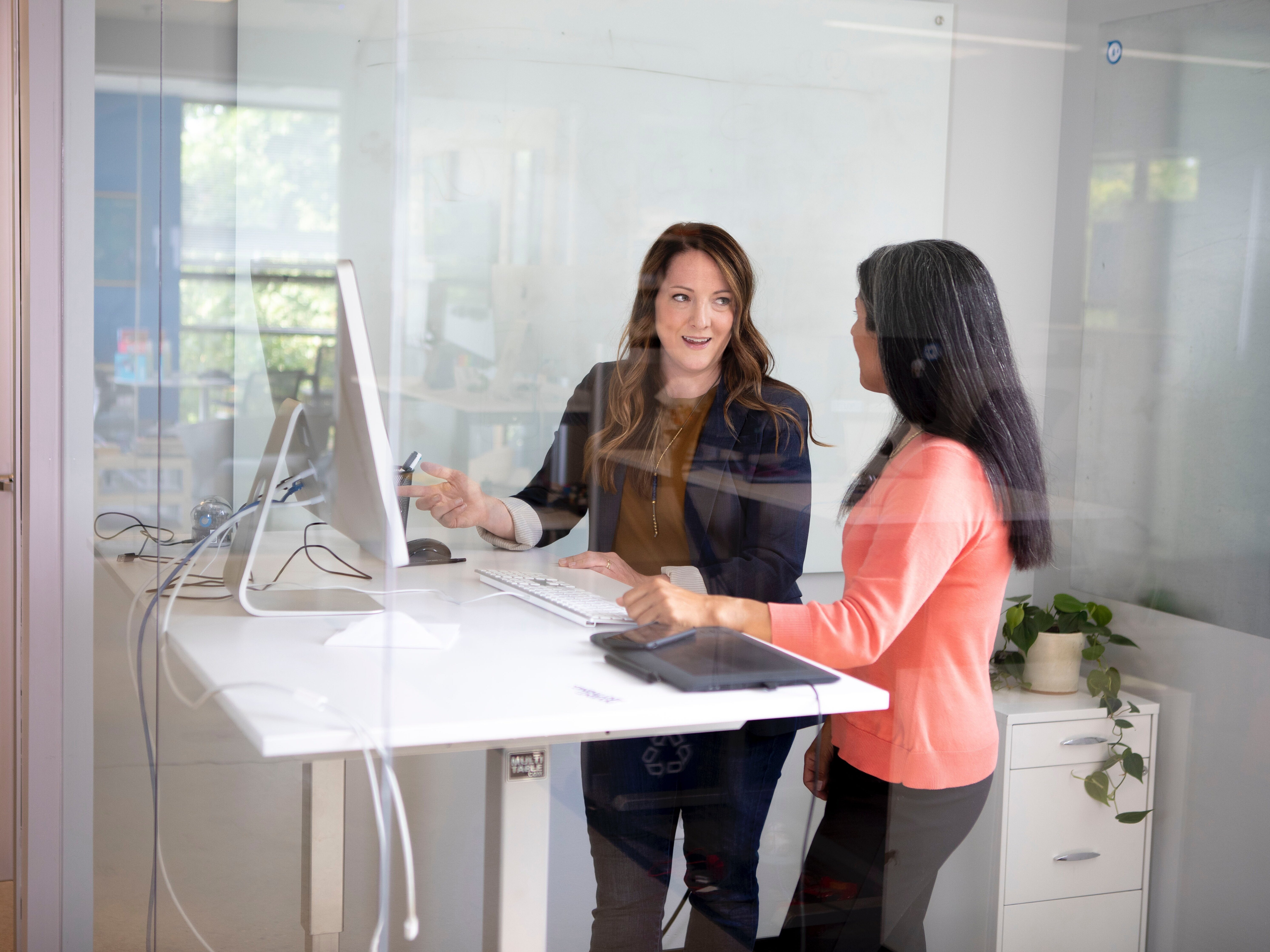 Zwei Frauen besprechen sich in einem Büro vor einem Bildschirm