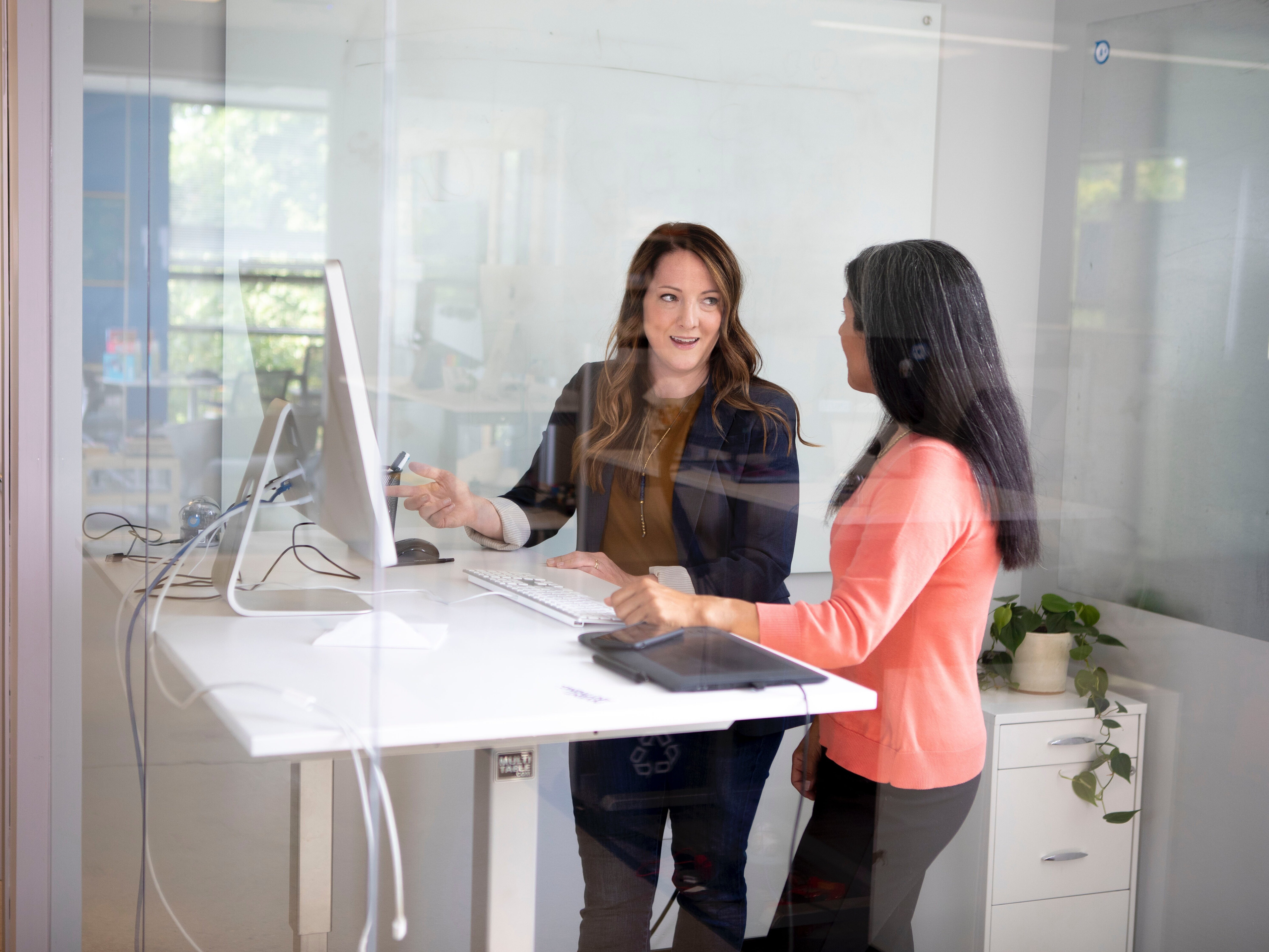 Zwei Frauen besprechen sich in einem Büro vor einem Bildschirm