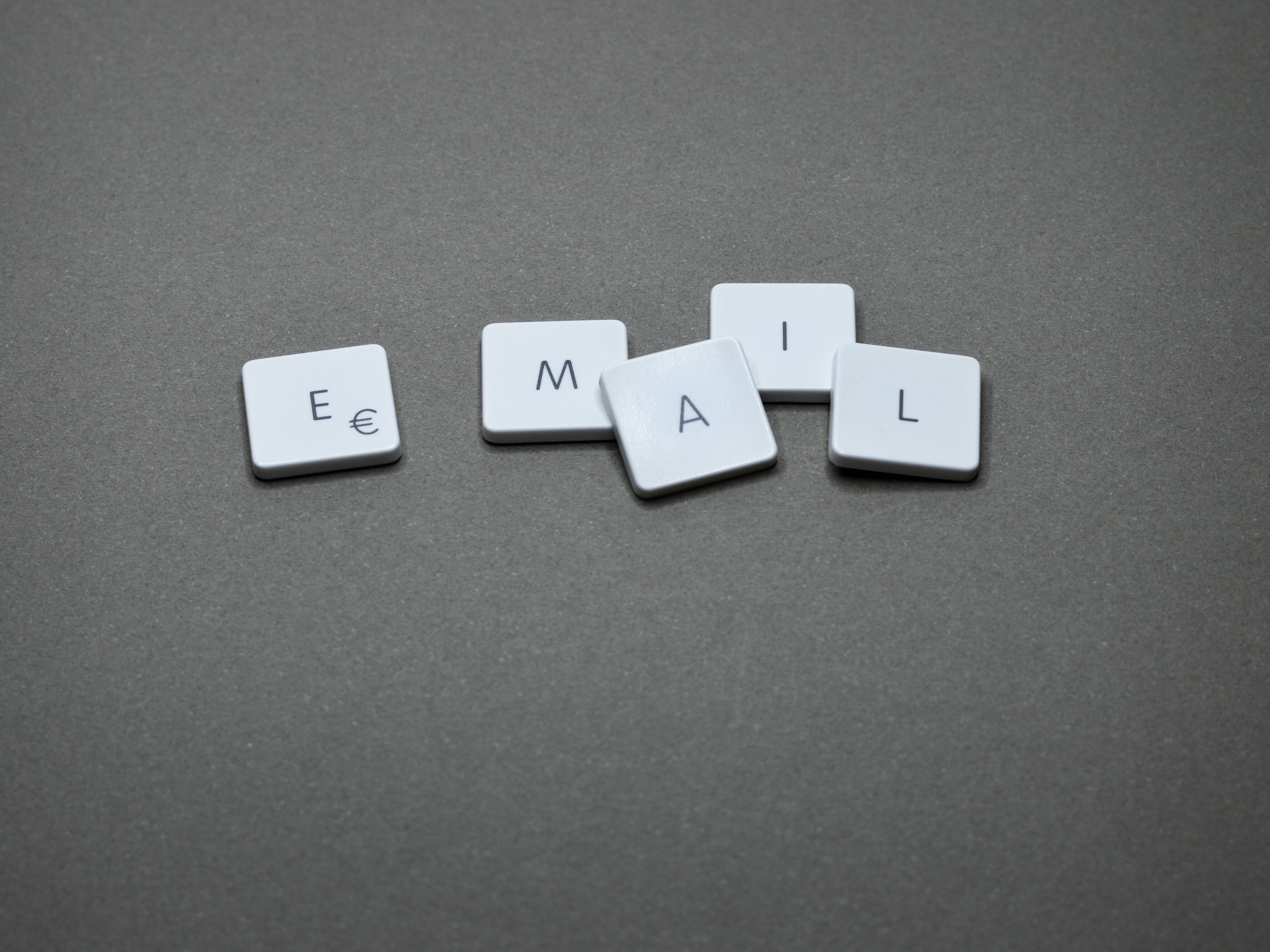 Einzelne Tastaturtasten mit den Buchstaben E, M, A, I, L auf grauem Hintergrund